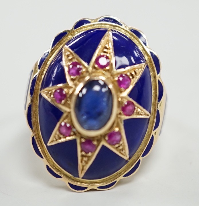 A yellow metal, blue enamel, ruby and cabochon sapphire set oval dress ring, the shank inscribed 'Sister My Sister?' size O, gross weight 13.7 grams.